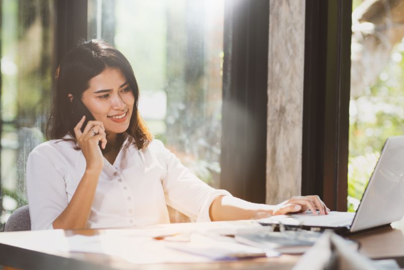 Woman taking a phone call and reading on her laptop