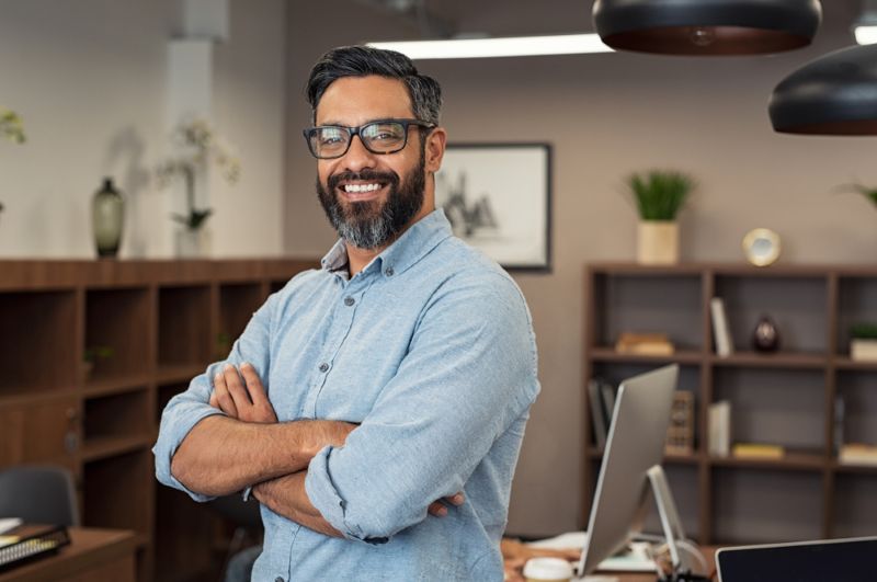 Latin man smiling in his office with arms crossed